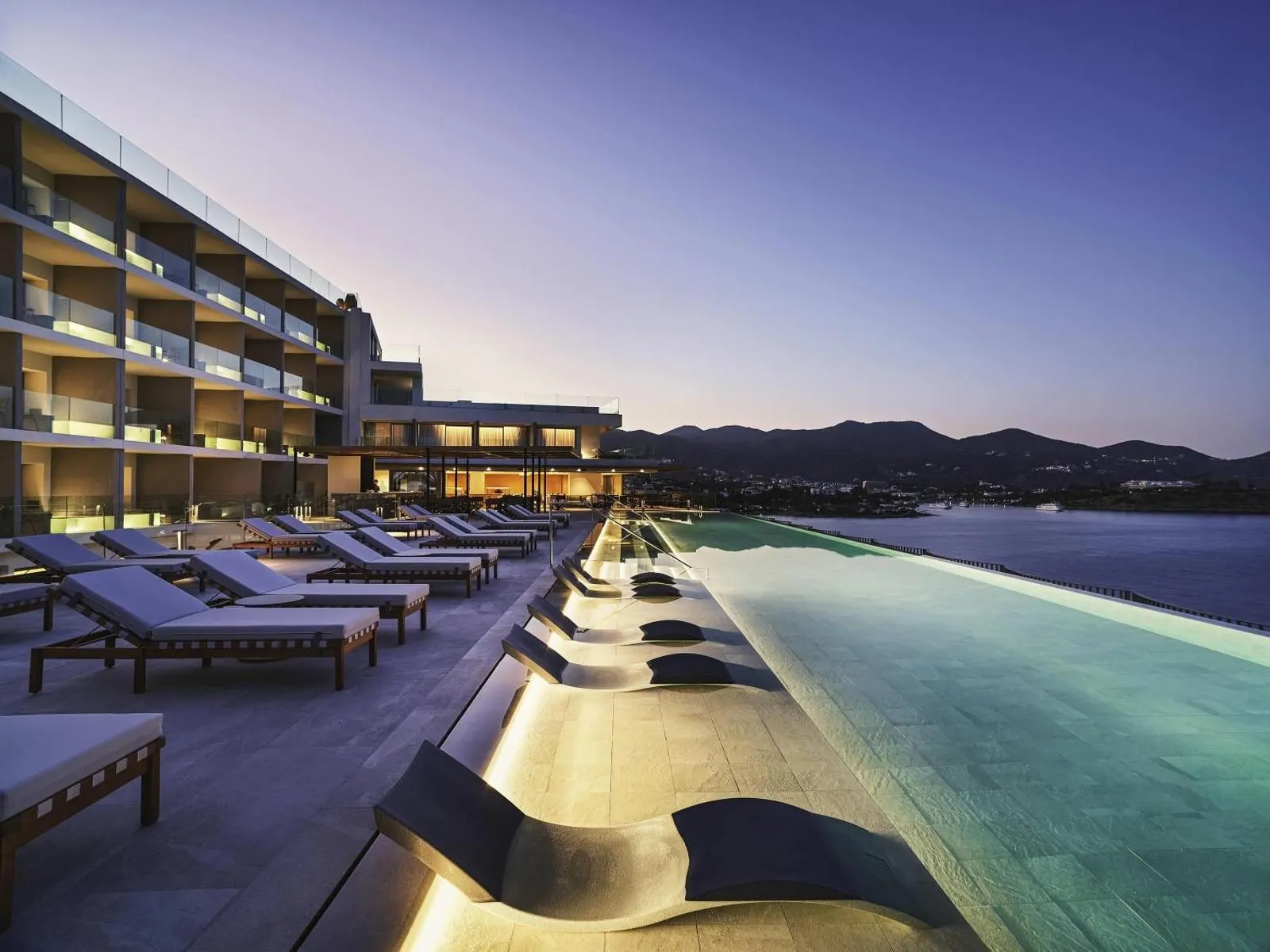 Poolside loungers beside hotel building at twilight