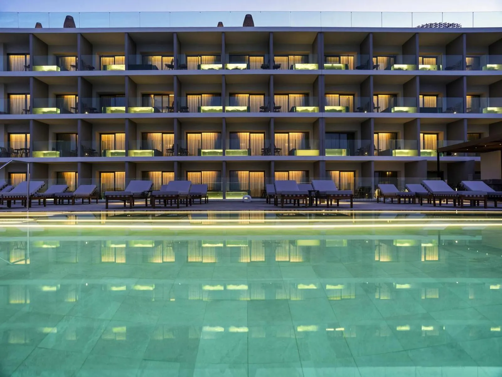 Hotel facade reflected in pool at dusk