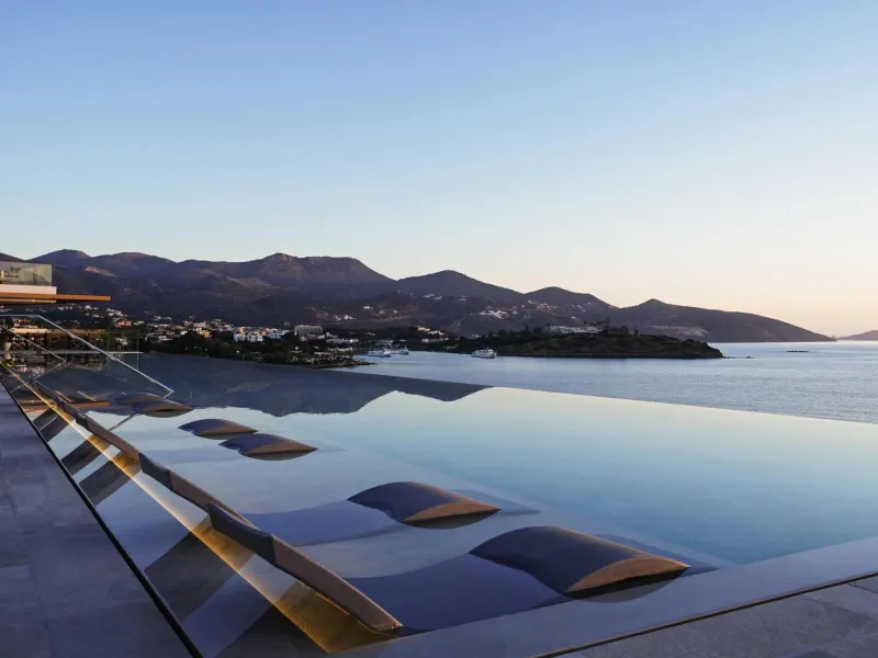 Infinity pool overlooking sea and mountains at dusk