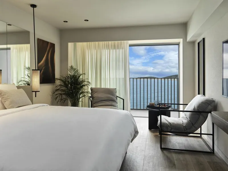 Bedroom with armchair and ocean view balcony