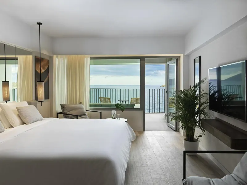Spacious room with bed, seating area and sea view