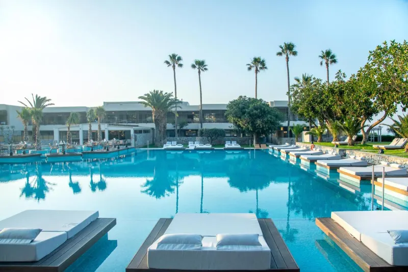 Poolside loungers with resort building and palm trees