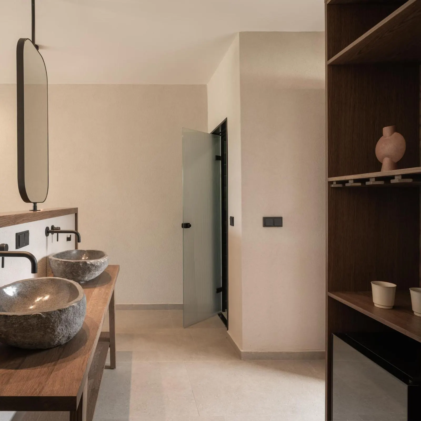 Bathroom with stone vessel sinks and wooden shelving