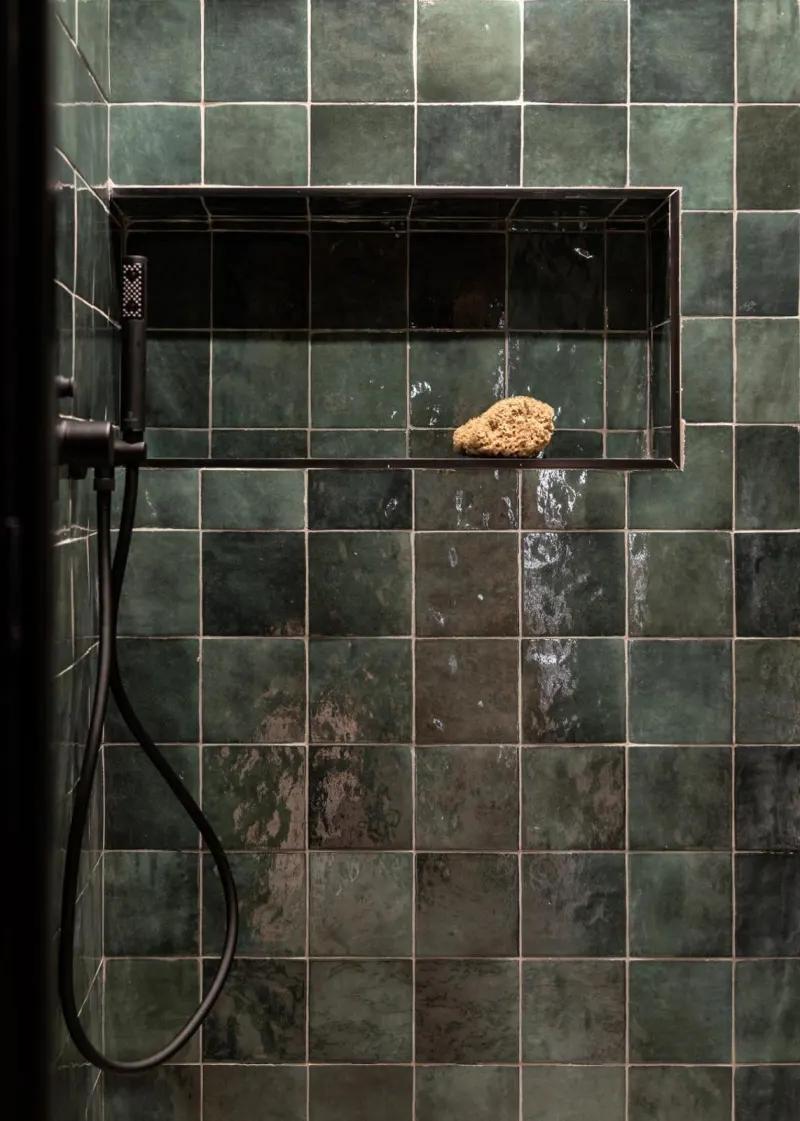 Green tiled shower with wooden sponge