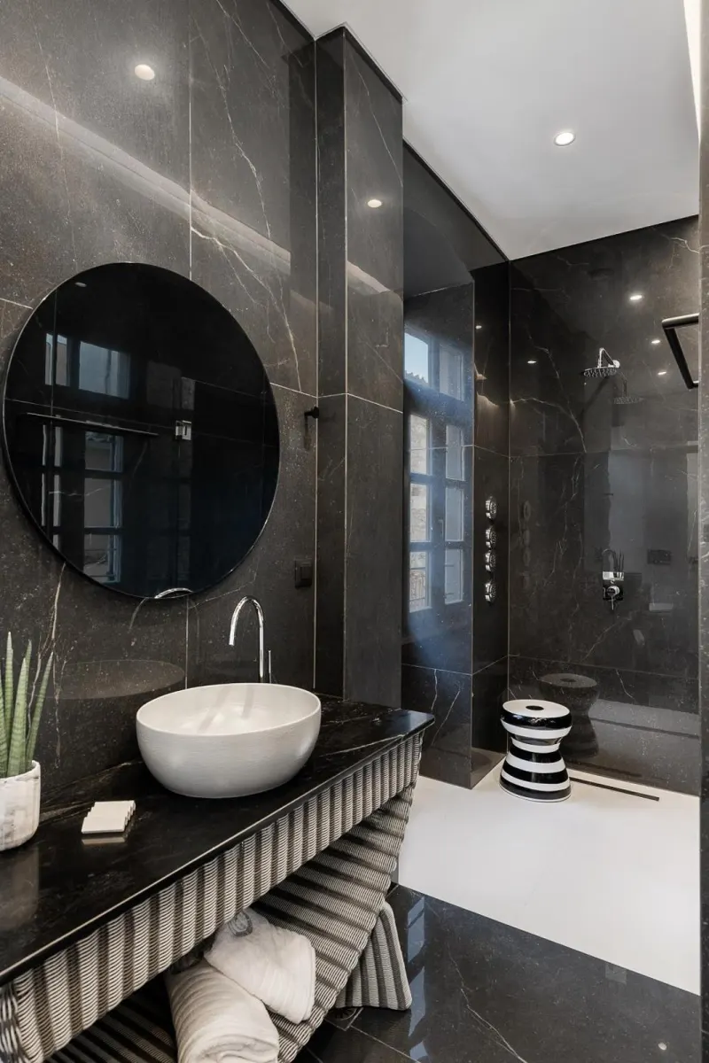 Modern dark marble bathroom with round mirror