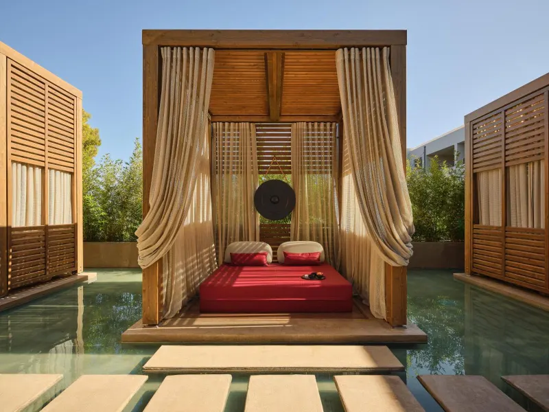 Wooden cabana with red daybed over pool