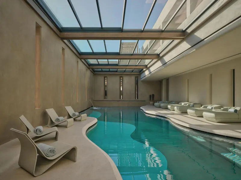 Indoor spa pool with glass ceiling and loungers
