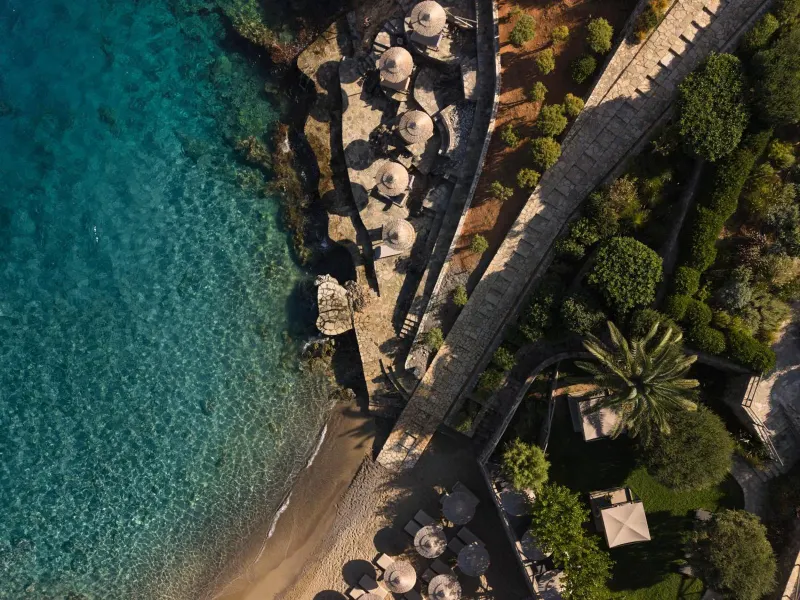 Aerial view of coastal path and beach with umbrellas