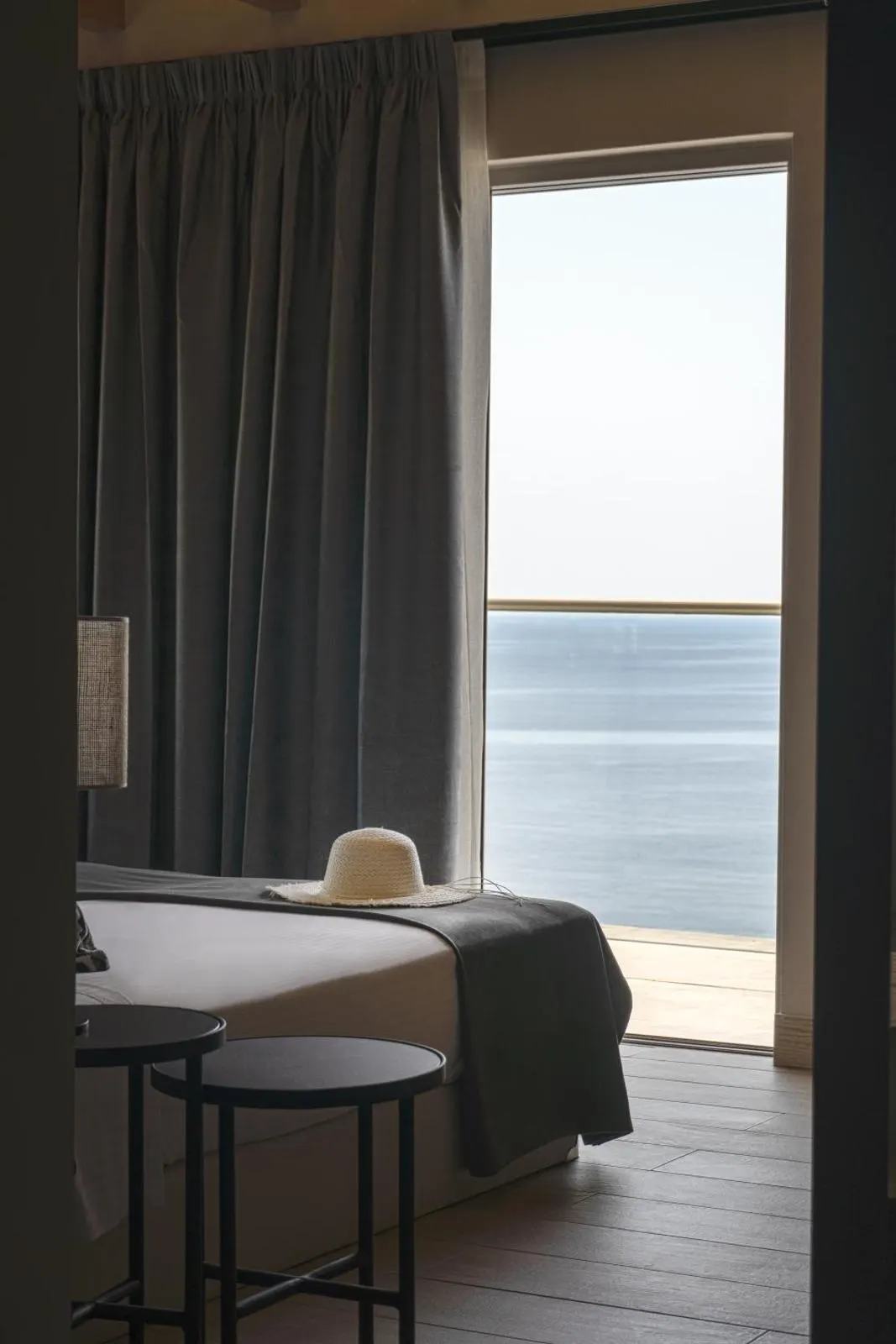 Bed by window with ocean view and hat