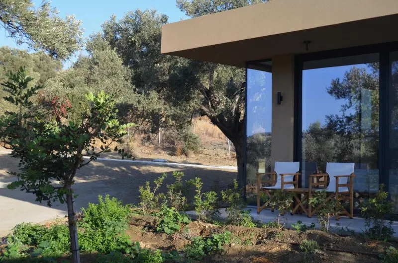 Terrace seating outside glass bungalow amid greenery