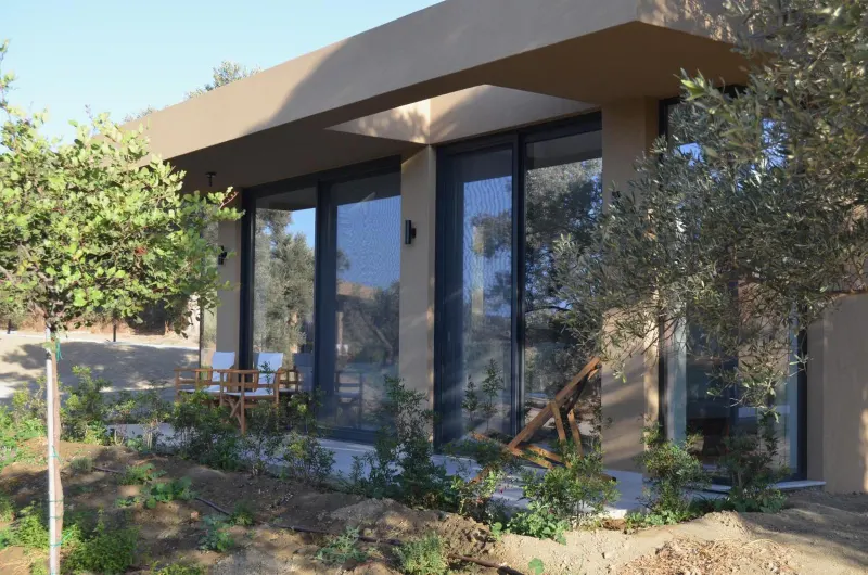 Bungalow exterior surrounded by trees and outdoor chairs