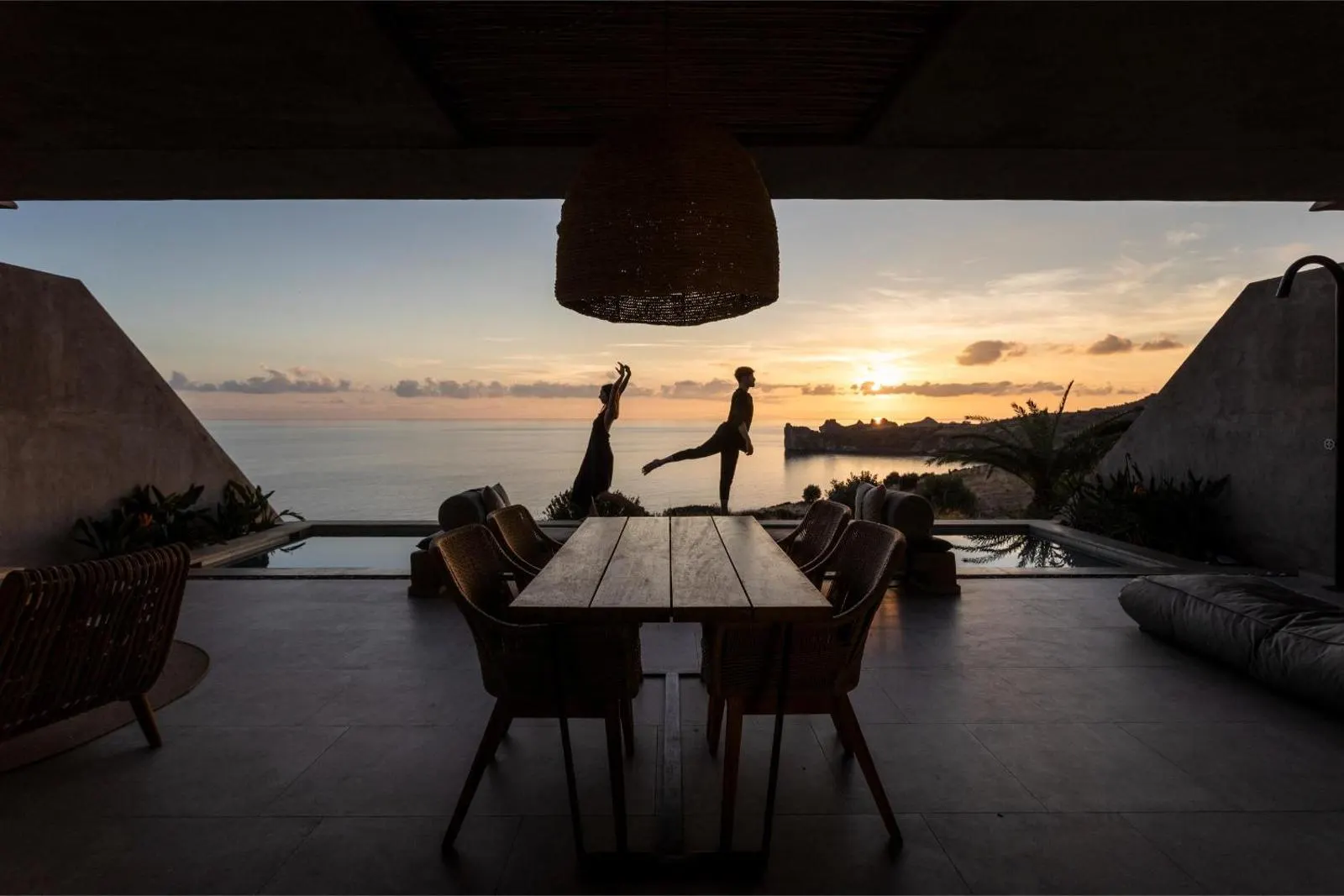 Couple dancing on terrace at sunset by pool