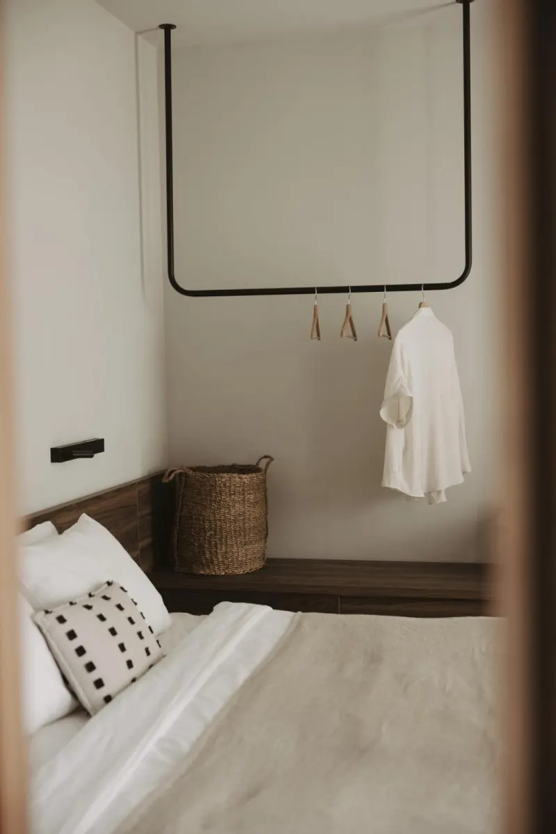 Bed with hanging clothes rail and woven basket