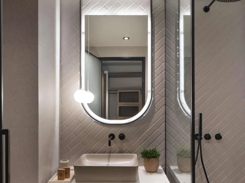 Modern bathroom with round mirror and herringbone tile