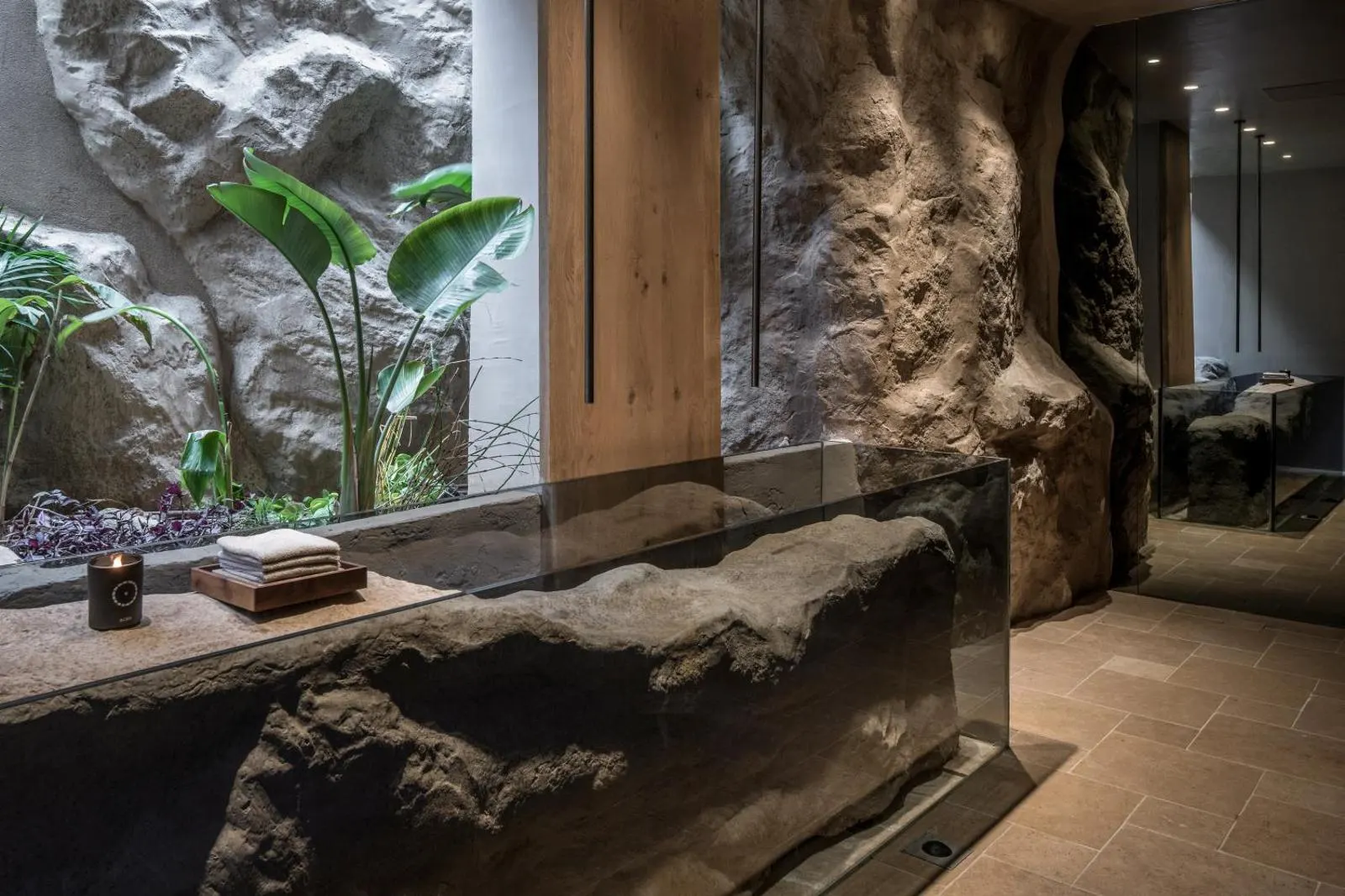 Sculpted stone counter with plants near mirrored wall