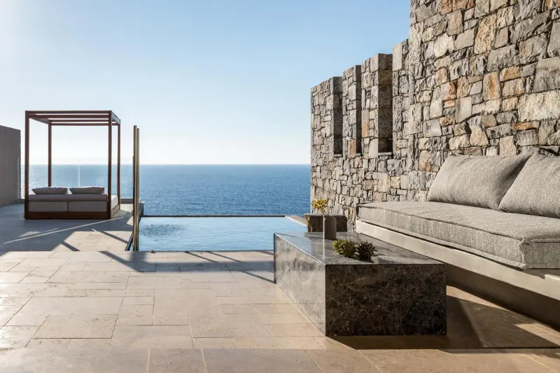 Stone-walled terrace lounge overlooking infinity pool and sea