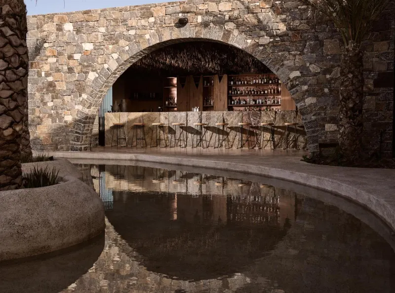 Stone archway bar reflected in poolside water