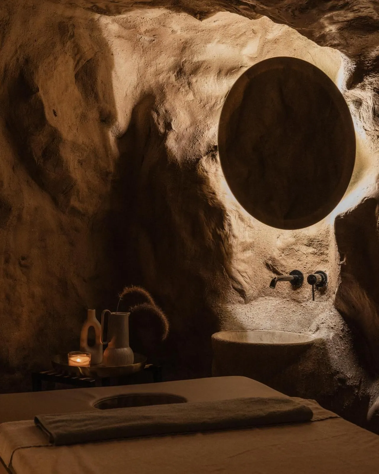Cave-style spa bathroom with round mirror