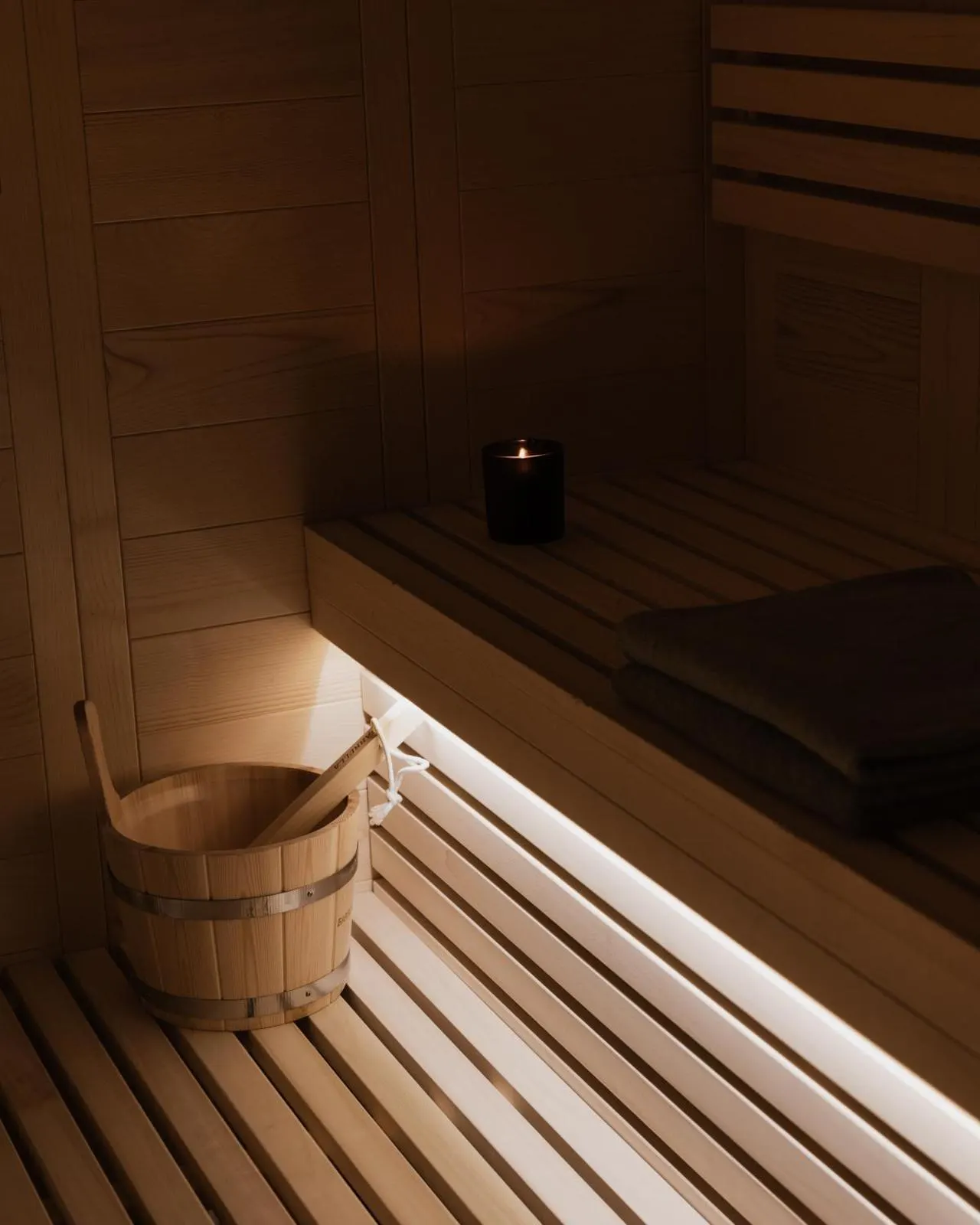 Wooden sauna interior with bucket and candle