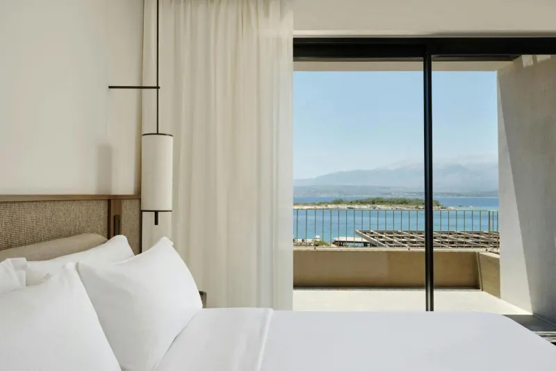 Hotel bed with balcony view of sea and island